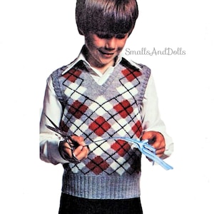 May include: A boy wearing a grey, white and red argyle knit waistcoat. The waistcoat has a V-neck and is sleeveless. The boy is holding a pair of scissors and a blue paper aeroplane.