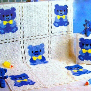 Puede incluir: Una manta de bebé de crochet blanco con aplicaciones de ositos de peluche azules. La manta está hecha de cuadrados con un osito de peluche en cada cuadrado. Hay una almohada más pequeña con una aplicación de osito de peluche azul.