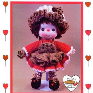May include: Crochet doll pattern for a chocolate chip cookie doll. The doll is wearing a red dress with a brown apron and a white and brown hat. The pattern is from "Lollipop Lane" by "Dumonlin Designs".