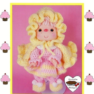 May include: Crochet pattern for a pink and yellow doll named "Pink Lemonade". The doll is wearing a yellow hooded cape and a pink dress with yellow trim. The pattern is by "Dumplin Designs" and is brought to you directly from "Cupcake Corner".