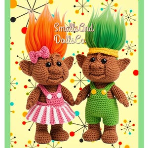 May include: Two crocheted troll dolls with brown skin and pointed ears. The left doll has orange hair, a pink bow, and a pink and white striped dress. The right doll has green hair, a yellow headband, and green overalls. Text reads Smalls And Dolls Co.
