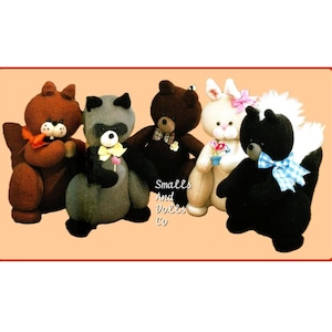 May include: Five plush stuffed animals: a brown squirrel, a gray raccoon, a brown bear, a white bunny, and a black skunk. Each has unique details like bows and accessories. The text "Smalls And Dolls Co" is visible.