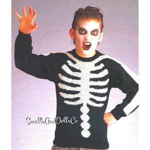 Puede incluir: Un suéter de punto negro y blanco con un diseño de esqueleto. El suéter lo lleva un niño con maquillaje de Halloween.