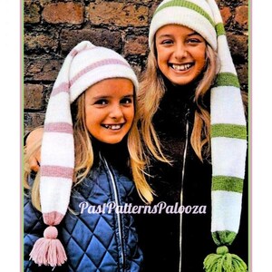 May include: Two people wearing white knit hats with long, striped, pointed tops and tassels. One hat has pink stripes and tassel, the other has green stripes and tassel. The text "Past Patterns Palooza" is visible.