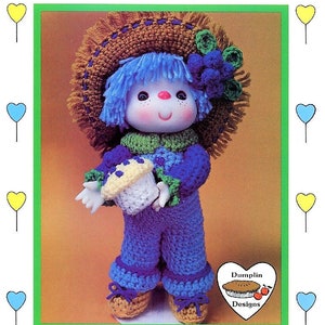 May include: Crochet doll pattern for a blueberry cupcake doll. The doll is wearing a blue dress, a brown hat, and holding a white cupcake with blue frosting. The pattern is from "Lollipop LANE".