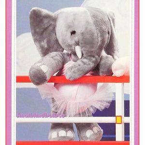 May include: A gray plush elephant wearing a pink tutu, standing behind a red and white fence. The elephant has large ears, a trunk, and white tusks. The image has the text "SmallAndDollsCo" in the bottom left corner.