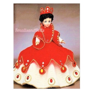 May include: A crocheted doll wearing a red and white dress with a crown. The dress is decorated with gold trim and rhinestones.