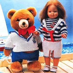 May include: A brown teddy bear and a doll wearing matching sailor outfits. The teddy bear is wearing a white and blue striped sweater with a red bow tie and blue shorts. The doll is wearing a white and blue striped sweater with a red bow tie and a white skirt with red and blue trim.