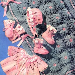 May include: A crocheted baby set in pink and gray. The set includes a blanket, a hat, a jacket, and booties. The blanket has a floral design and is edged with pink ribbon. The hat, jacket, and booties are all crocheted in a delicate pink yarn.