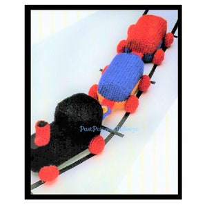 Peut inclure: Un train jouet composé de trois wagons. La locomotive est noire avec des roues rouges et une cheminée rouge. Le wagon suivant est bleu avec des roues rouges et le dernier wagon est rouge avec des roues rouges. Les wagons sont sur une voie blanche.