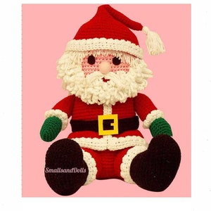 May include: A handmade crochet Santa Claus doll. The doll is primarily red with white trim, a white beard, and a red hat. It has a black belt with a gold buckle, green gloves, and brown boots. The doll is sitting down.