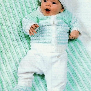 May include: A baby wearing a white and green crocheted outfit with a white crocheted hat. The baby is lying on a green and white striped crocheted blanket.