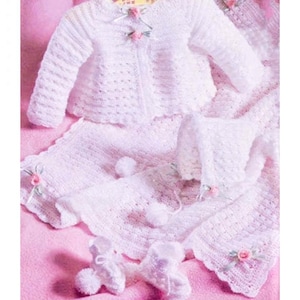 May include: A white crocheted baby outfit set with a cardigan, skirt, bonnet, and booties. The set is decorated with white pom-poms and pink flowers.