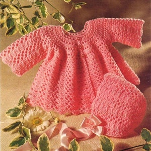 Puede incluir: Una chaqueta de bebé de ganchillo rosa y un gorro a juego. La chaqueta tiene cierre de botón y mangas largas. El gorro es un estilo sencillo de gorro.