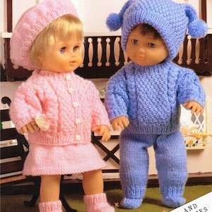 May include: Two knitted doll outfits, one pink and one blue, with matching hats. The outfits are designed for dolls and premature babies. The pink outfit includes a cardigan, skirt, and booties. The blue outfit includes a sweater, pants, and booties. The outfits are shown on dolls sitting on a bench.