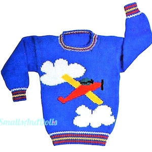 Könnte beinhalten: Blauer Strickpullover mit einem roten Flugzeug, das durch weiße Wolken fliegt. Der Pullover hat gelbe, rote und weiße Streifen am Hals und an den Ärmeln.