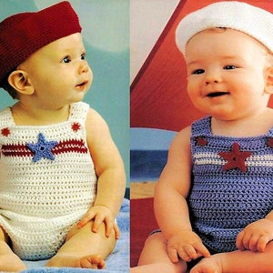 May include: Two babies wearing crocheted outfits. One baby is wearing a white crocheted outfit with red and blue stripes and a red star. The other baby is wearing a blue crocheted outfit with white stripes and a red star. Both babies are wearing crocheted hats.