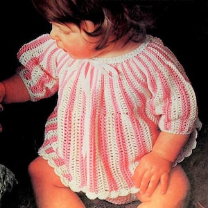 May include: A pink and white striped crocheted baby dress with a white crocheted lace trim. The dress has a bow at the neckline.
