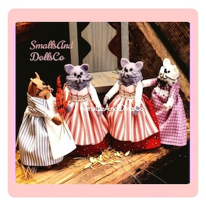 May include: Four anthropomorphic mouse dolls with stitched facial features and whiskers. Each mouse wears a fabric dress with distinct patterns including blue stripes, red and white stripes, and a purple plaid print. The text SmallsAndDollsCo is visible.