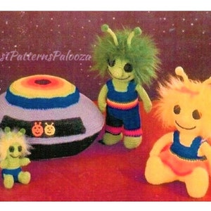 Op de afbeelding: Een haakpatroon voor een vliegende schotel, twee aliens en een klein alien. De vliegende schotel is paars met een regenboogrand. De aliens zijn groen en geel met blauwe en oranje kleding.