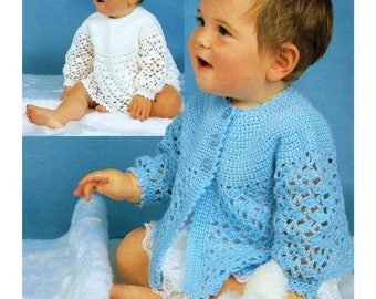 May include: A baby wearing a light blue crocheted cardigan with a white crocheted undershirt. The cardigan has a button closure and a lacy pattern.