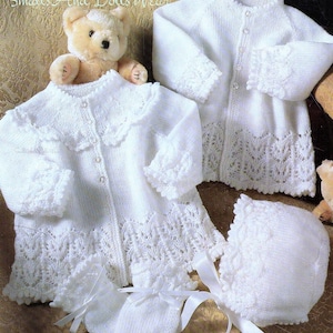 Peut inclure: Ensemble de vêtements en tricot blanc pour bébé comprenant un cardigan, une robe, un bonnet et des mitaines. L'ensemble est orné de dentelle délicate et de boutons. "Small And Dolls Wear" est écrit sur le fond.