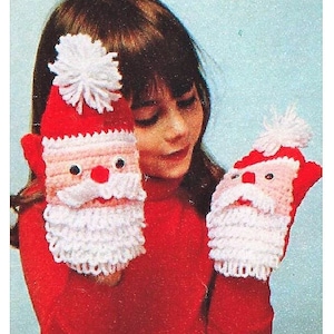 May include: A child wearing a red sweater holds two crocheted Santa Claus mitten puppets. The puppets have white beards, pink faces, and black eyes.