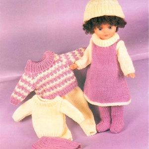 May include: A knitted doll outfit with a pink dress, yellow sweater, and matching trousers. The doll is wearing a yellow hat with a pink pom-pom.