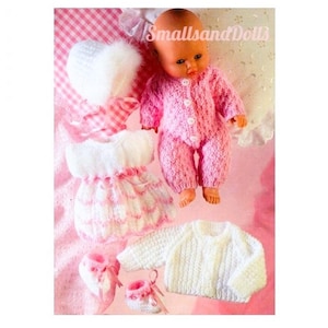 May include: A set of knitted doll clothes in pink and white, including a dress, a hat, a sweater, and booties. The doll clothes are designed for a small doll, such as a baby doll.