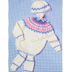 May include: A cream-coloured knitted baby set, including a sweater, hat, and leg warmers. The sweater and hat feature a pink and blue geometric pattern. The leg warmers have blue stripes. The set is displayed on a blue and white gingham background.