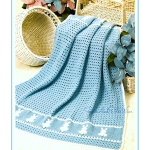 May include: A light blue crocheted blanket featuring a white border with a repeating pattern of white bunny silhouettes. The blanket has a textured stitch throughout and includes the text "Smalls And Dolls Wear" in a script font.