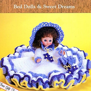 May include: A crocheted doll bed with a white and blue ruffled skirt, a yellow trim, and a doll wearing a white dress with a blue hat and a matching basket. The text "Bed Dolls & Sweet Dreams" is at the top of the image.