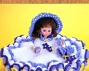 May include: A doll wearing a white and blue crocheted dress with a matching bonnet and a small basket. The doll has brown hair and blue eyes. The text Bed Dolls & Sweet Dreams and Free Gift Tags is visible on the image background.