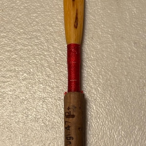 May include: A wooden clarinet reed with a red string tied around the top and the text "Chiarugi 47 R" printed on the side.
