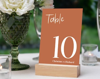 May include: A table number card with a brown background and white text. The card says "Table 10" and "Christine and Richard".