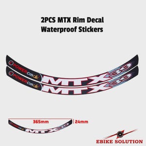 Può includere: Due adesivi neri curvi per cerchioni con testo bianco MTX 39 e marchio rosso Power Circle. Gli adesivi misurano 365 mm di lunghezza e 24 mm di larghezza. Il testo 2PCS MTX Rim Decal Waterproof Stickers è visualizzato sopra gli adesivi.