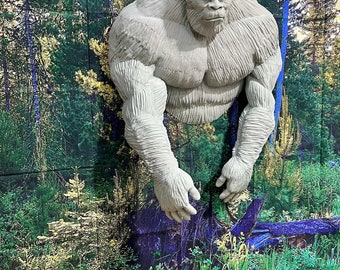 May include: A white, sculpted figure of Bigfoot, a mythical creature, standing in a forest setting. The figure is detailed with fur and has a realistic appearance.