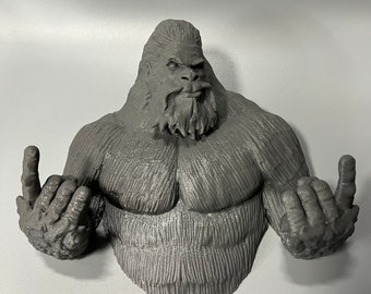 May include: A gray 3D printed figurine of a Bigfoot with a beard, giving the middle finger with both hands.