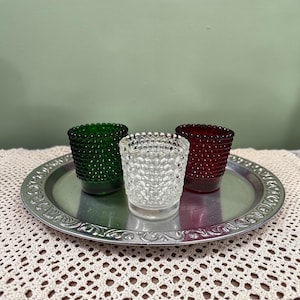 May include: A white ceramic mug with a black handle and the text "But First, Coffee" in a black, bold font. The mug is likely 4 inches tall and holds approximately 12 ounces of liquid.