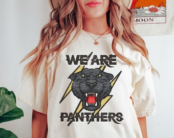 May include: A white t-shirt with a black panther graphic and the text "We Are Panthers" in yellow and black lettering.