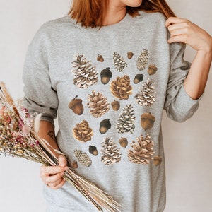 May include: A gray sweatshirt with a pattern of brown pine cones and acorns.
