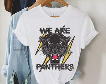 May include: White t-shirt with a black panther graphic and the text "We Are Panthers" in yellow and black.