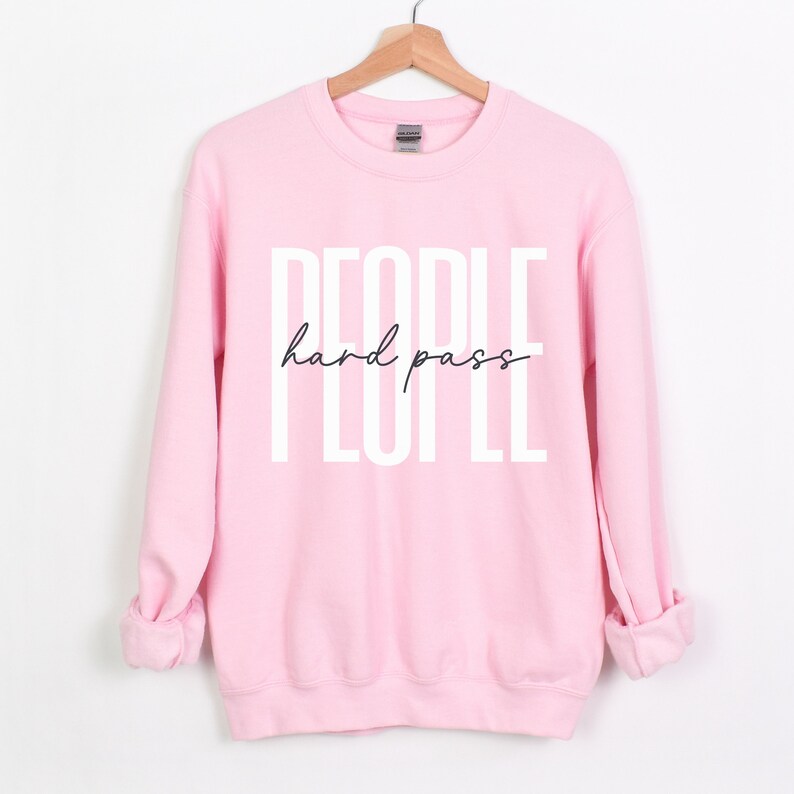 Puede incluir: Sudadera rosa con el texto "PEOPLE hard pass" en letras blancas.