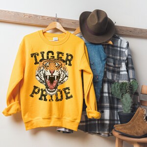May include: Yellow sweatshirt with a tiger face graphic and the text "Tiger Pride" in black distressed lettering.