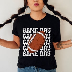 May include: Black t-shirt with a white graphic of a football and the text "GAME DAY" repeated multiple times.