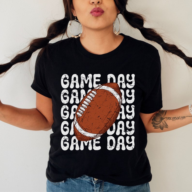 May include: Black t-shirt with a white graphic of a football and the text "GAME DAY" repeated multiple times.