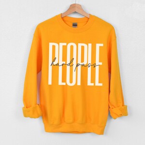 Puede incluir: Una sudadera amarilla con el texto "PEOPLE hard pass" impreso en blanco en la parte delantera.