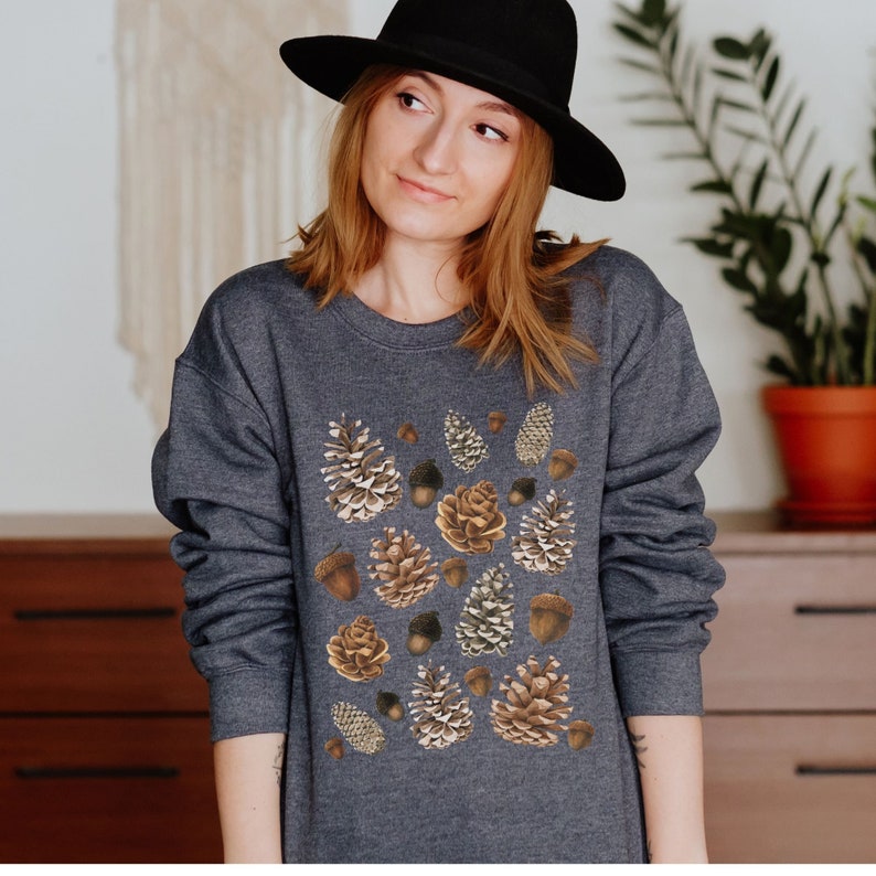 May include: A dark gray sweatshirt with a pattern of brown and beige pine cones and acorns.