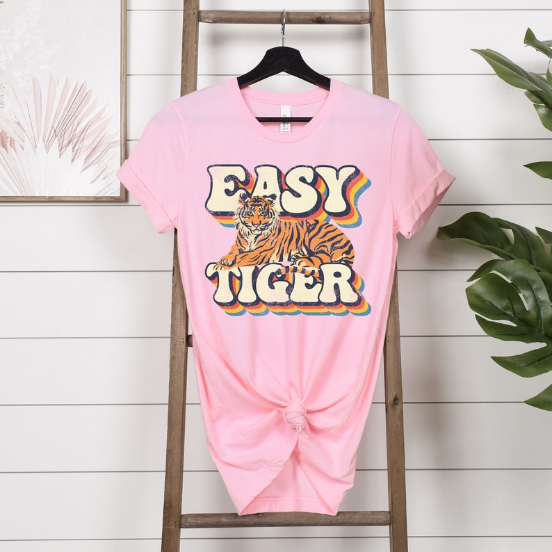 May include: Pink t-shirt with a retro-style graphic of a tiger and the text "Easy Tiger".