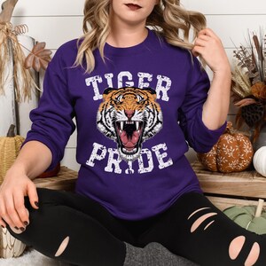 May include: Purple sweatshirt with a white graphic of a tiger with the text "Tiger Pride" in a distressed font.